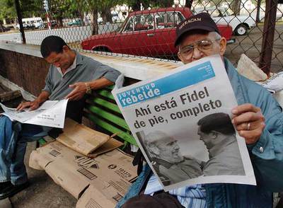 Dos hombres leen el diario  Juventud Rebelde,  con las imágenes de Castro y Chávez, ayer en La Habana.