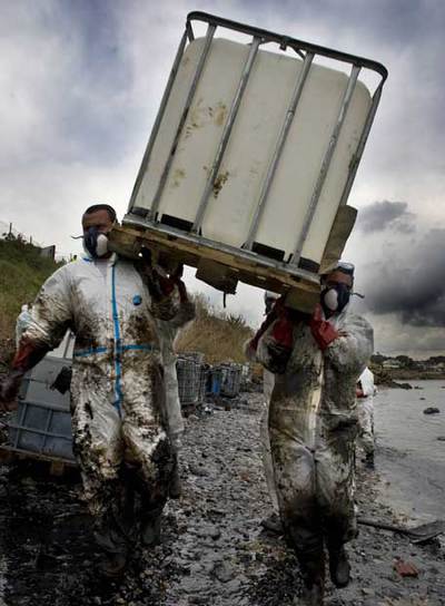 Miembros del equipo de limpieza trabajan en la recogida de carburante del  Sierra Nava  en la playa del Chinarral, en la bahía de Algeciras.