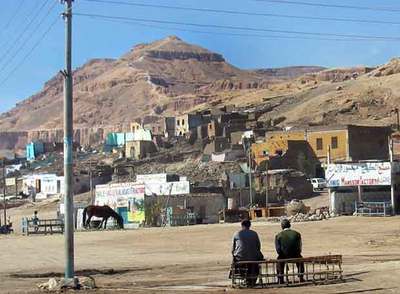 Imagen de Qurna. Delante, los edificios en curso de demolición. Detrás, la montaña piramidal llamada El Qurn, sagrada para los antiguos egipcios.