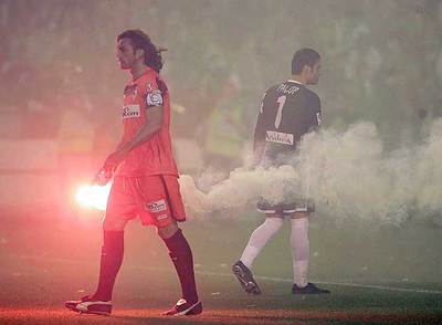 Javi Navarro, capitán sevillista, retira una bengala junto a su portero Palop.