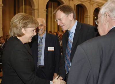 Angela Merkel y Janez Potocnik se saludan en presencia de Fotis Kafatos en Berlín.