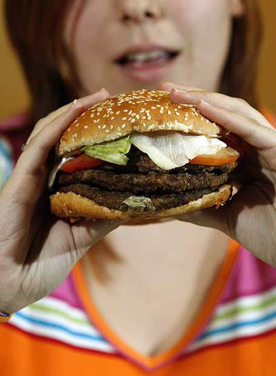 Una mujer come una hamburguesa de Burger King.