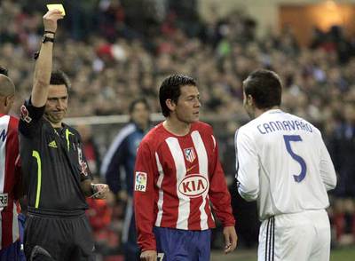 El árbitro muestra a Cannavaro la tarjeta amarilla durante el partido Atlético-Real Madrid.