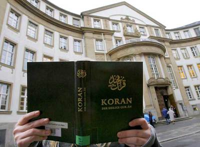 Una mujer posa con un ejemplar del Corán frente a un juzgado de Francfort, en Alemania.