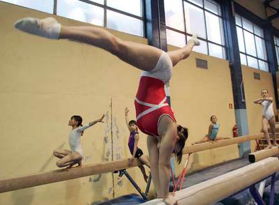 Gimnastas del club de San Blas practican sobre la barra.