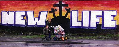 Una familia norirlandesa pasa ante una pintada a favor de la paz en el centro de Belfast.