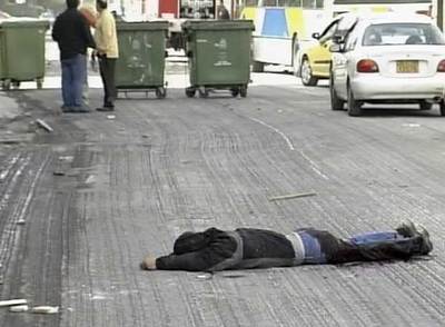 Un herido en la trifulca entre aficionados griegos yace en una calle de Peanía.