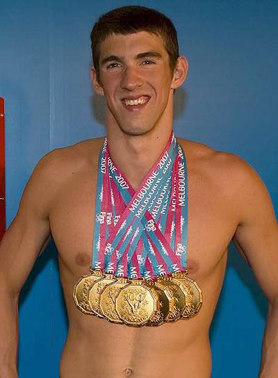 Michael Phelps exhibe con satisfacción todas sus medallas.
