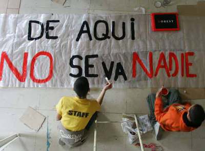 Unos niños pintan el lema de resistencia de la parroquia de San Carlos Borromeo,  De aquí no se va nadie,  extraído de un poema de León Felipe.