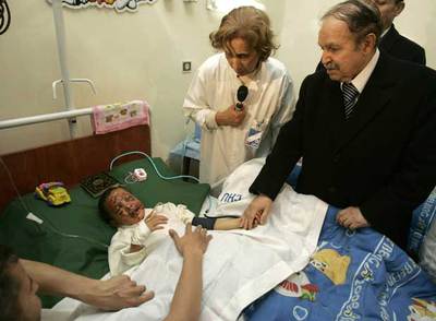 El presidente argelino sostiene la mano de un niño víctima del atentado.