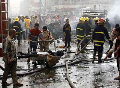 Residentes y equipos de rescate en el lugar de uno de los atentados con coche bomba cometidos ayer en Bagdad.