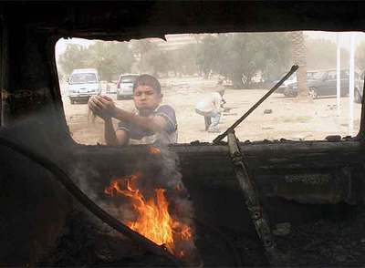 Un niño iraquí echa tierra para apagar las llamas de un vehículo después de que un coche bomba explotara ayer cerca de la Zona Verde de Bagdad.