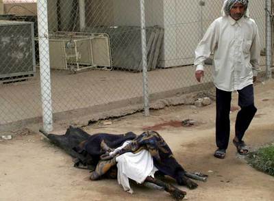 Un iraquí pasa junto a los restos carbonizados de una víctima de la explosión de un coche bomba en Kerbala.