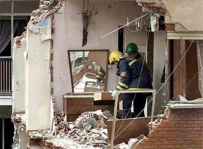 Un bombero ayuda a un vecino de las viviendas afectadas a recoger parte de sus enseres.