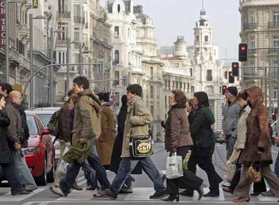 Varias personas cruzan un semáforo en la Gran Vía de Madrid