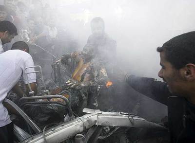 Varias personas sacan al ocupante de un coche destruido por un ataque aéreo israelí ayer en Gaza.