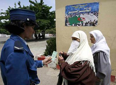 Una agente comprueba la documentación de dos votantes.