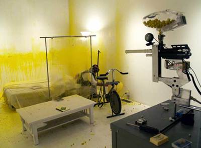 Wafaa Bilal en su jaula y el fusil apuntando.