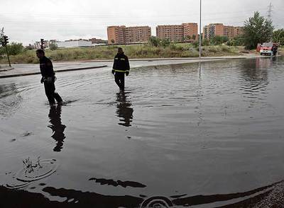 Dos bomberos observan la inundación en la rotonda de Fuente Carrantona, en Moratalaz. Abajo, atasco junto al Arco del Triunfo. rn R. GUTIÉRREZ