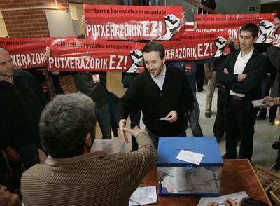 El presidente del PNV, Josu Jon Imaz, en el momento de votar en San Sebastián, hostigado por varios radicales con carteles.