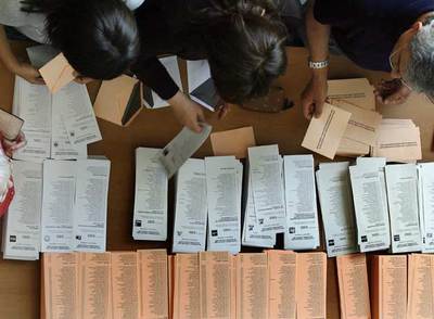 Varios electores cogen ayer papeletas en un colegio electoral.