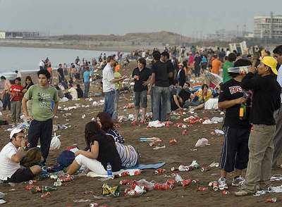 Jóvenes apuran sus bebidas en la playa de Sant Sebastià de Barcelona antes de que acabe la verbena.