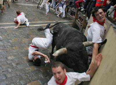 Un  miura  coge a tres corredores en la curva de Mercaderes, ayer en Pamplona.