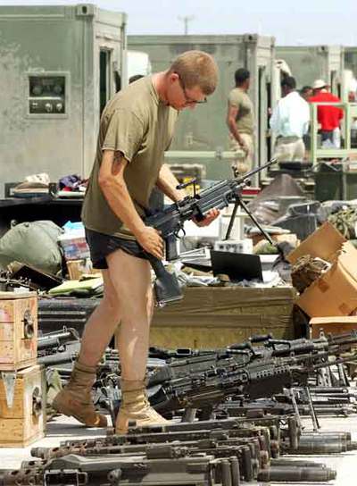 Un  marine  comprueba su arma antes de entregarla, una vez que ha terminado su periodo militar en Irak.