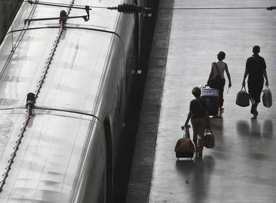 Tres pasajeros afectados por los retrasos caminan por uno de los andenes de la estación de Atocha de Madrid.