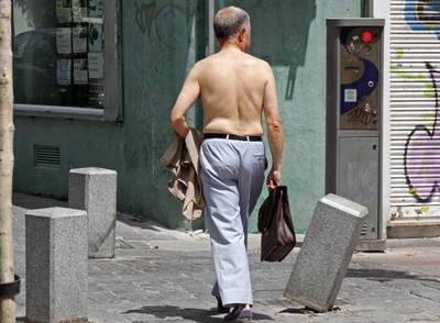 Un hombre pasea sin camisa por el centro de Madrid.