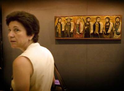 Una visitante pasa por delante de una obra incluida en 'La luz de las imágenes', en la Colegiata Basílica de Santa María, sede principal de la muestra que acoge Xátiva.