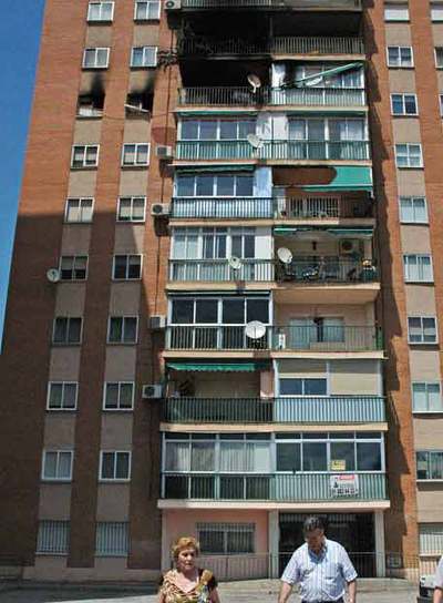 Una pareja se lleva sus pertenencias del edificio incendiado.
