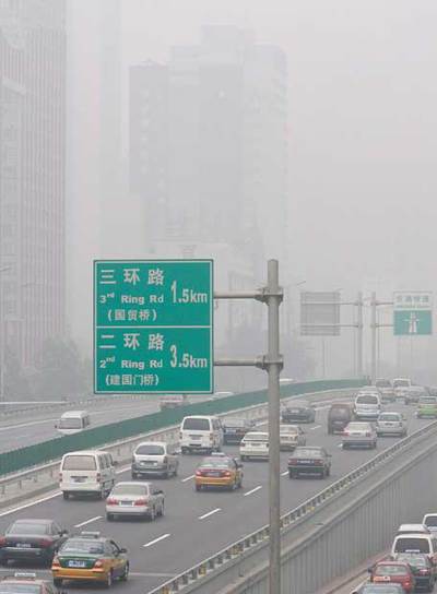 Imagen de una congestionada avenida de Pekin bajo una nube de contaminación.