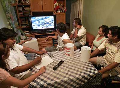 Un grupo de peruanos sigue las noticias de su país por televisión.