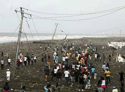 Decenas de jamaicanos caminan después del huracán por una carretera cubierta de barro cercana al aeropuerto de Kingston.