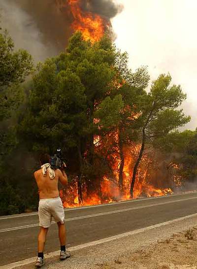 Un camarógrafo toma imágenes del fuego  cerca de Zaharo.