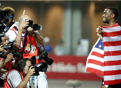 Tyson Gay posa para los fotógrafos con la bandera estadounidense tras su triunfo.