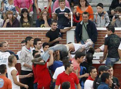 Varios asistentes al encierro sacan a un herido.