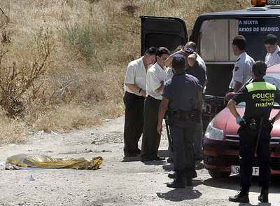 La policía y varios empleados de los servicios funerarios, ante el cadáver de la víctima.
