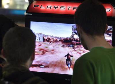 Dos jóvenes miran la pantalla de un vídeojuego en un centro comercial.