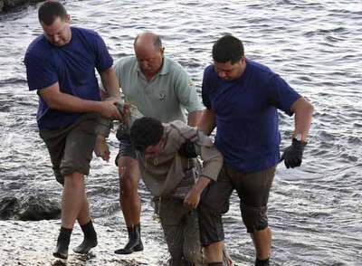 El cadáver de uno de los inmigrantes fallecidos es sacado de las aguas de la playa de Risco Verde.