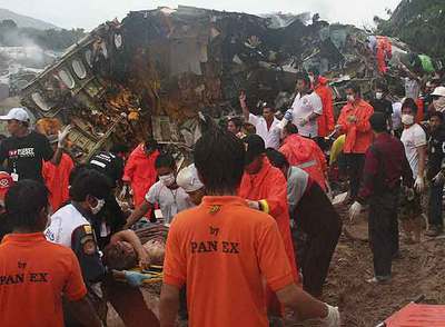 Trabajadores de los equipos de rescate evacuan a los heridos del avión que se estrelló ayer en la isla tailandesa de Phuket.