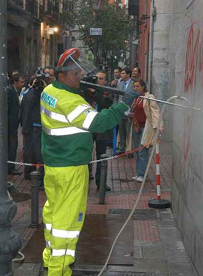 Un operario limpia con agua y decapante una pintada.