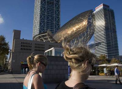 Las escamas de bronce del  Peix d'Or,  escultura de Frank Gehry de 1992, brillan al sol en el puerto Olímpico de Barcelona, con las torres del edificio del hotel Arts y la torre Mapfre al fondo . 