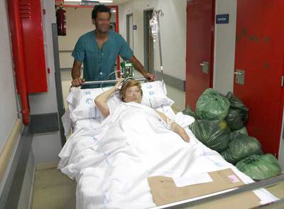 Una enferma es trasladada por uno de los pasillos del Hospital de la Paz, junto a un cúmulo de residuos.