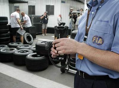 Un comisario de la FIA supervisa ayer la presión de los neumáticos cerca del  box  de McLaren.