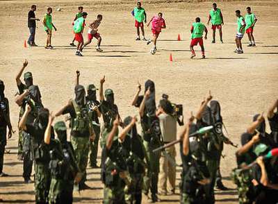 Los jugadores de Palestina se entrenan en Gaza. En primer plano, un grupo de milicianos.
