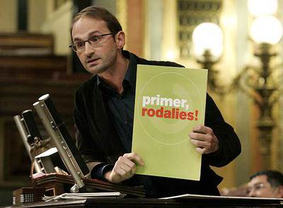 El diputado de ICV Joan Herrera muestra un cartel que dice  