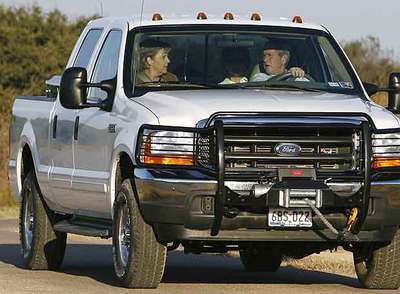 Angela Merkel, George Bush y Laura Bush (detrás), ayer en coche por el rancho de Crawford (Tejas).