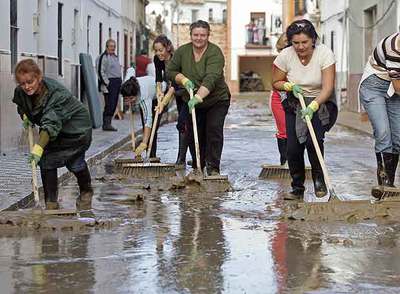 Vecinas de la barriada utrerana Coca de la Piñera limpian el lodo de las calles tras la inundación de la madrugada del miércoles. rn garcía corderornReyes Álvarez y su marido, Juan Gago, frente a su casa.